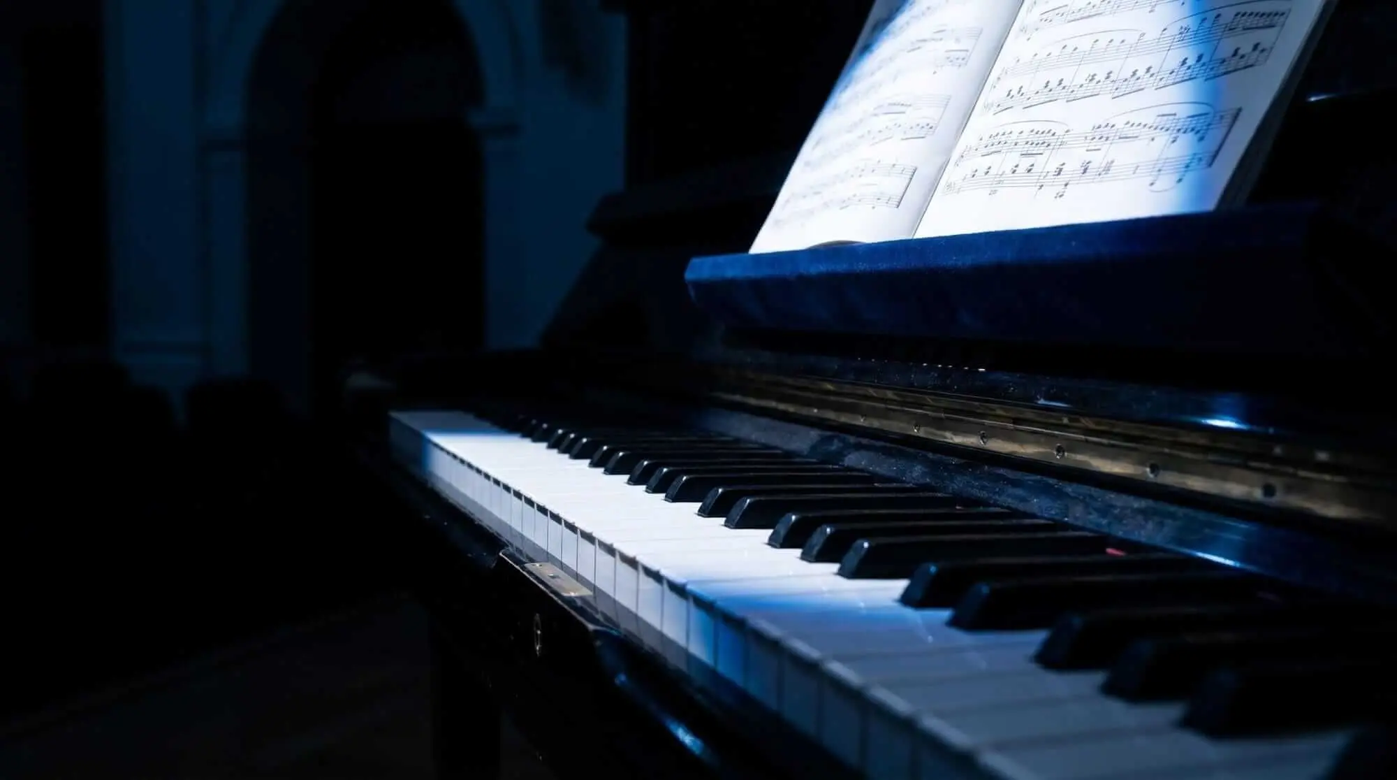 Dark atmospheric piano with illuminated sheet music, representing chord theory, harmony, composition, and musical performance.